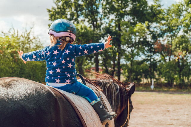 A little girl horseback riding